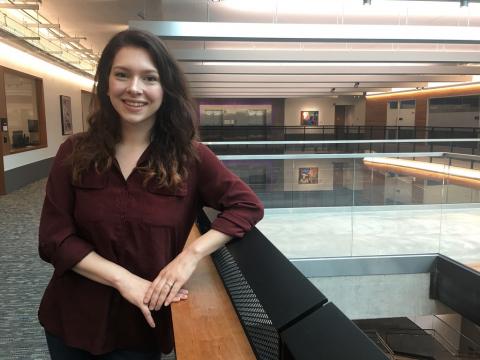 Photo of a young woman, smiling in the Gates Center atrium