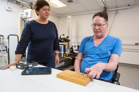 Fatma Inanici applies spinal stimulation as Joe Beatty begins a nine-hole peg test.