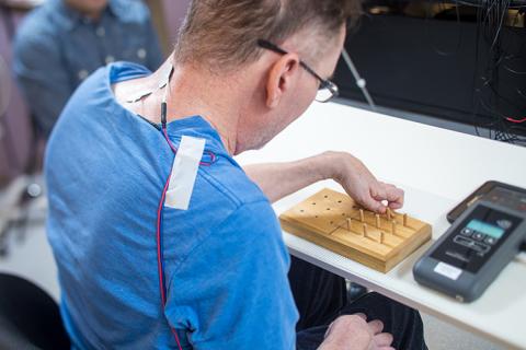 Joe Beatty performs the nine-hole peg test while stimulation is continuously applied to his cervical spinal cord.