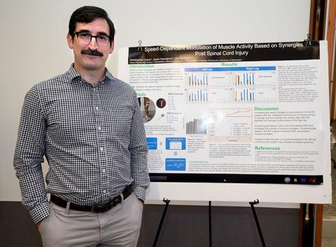 A man standing next to a research poster