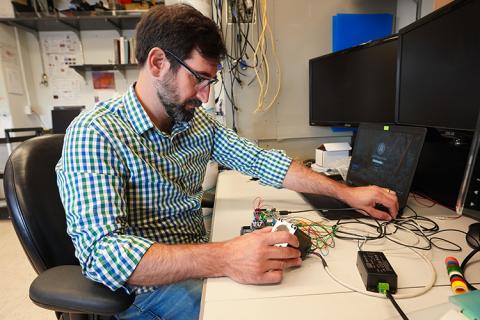 Chris Calvin, a science teacher at Mount Rainier High School in Washington state, developed a curriculum unit in the RET program that helps his students explore human enhancement through electromechanical methods, and the ethical implications of using this technology. Calvin’s experience in the CNT-affiliated Restorative Technologies Laboratory informed the development of his curriculum. A man, sitting at a desk, working on electronic equipment