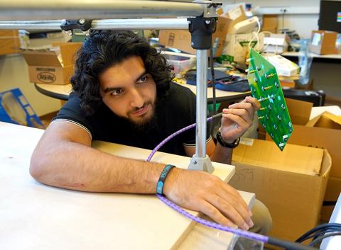 Usman Khan, a UW undergraduate working in the CNT-affiliated Sensor Systems Laboratory, plugs a wireless receiver into a system he developed to 3D-map the device’s electromagnetic field. Khan titled this system, “3DEVS: a 3D Electromagnetic Visualization System for the Design and Analysis of Wirelessly Powered Implants.” man adjusting high-tech device, which sits on a table