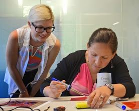 Aiva (left) oversees Claudia's soldering while she builds a SpikerBox